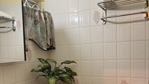 A bathroom with a white toilet, a sink with a mirror, a shower area, and a potted plant. - MoBay Life (Montego Bay)