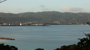 A coastal landscape with a calm sea, distant hills, and a small pier. - MoBay Life (Montego Bay)