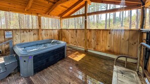 Une cabane en bois dotée d’un bain à remous, de planchers en bois et offrant une vue sur la forêt.