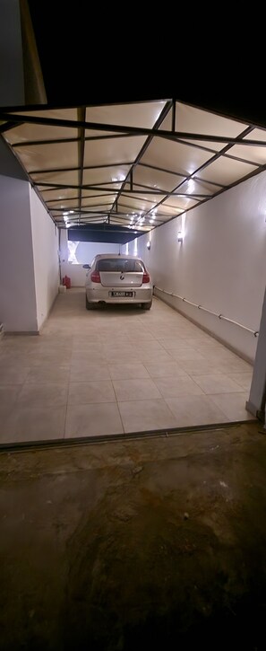 A parking garage with a white car parked in the center. - Villa hasdrubal swimming pool not overlooked (Djerba Midun)