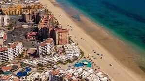 A coastal resort with multiple hotel buildings, a sandy beach, and a clear blue sea. - Bonita 602 (Puerto Peñasco)