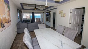 A dining area with a marble table and cushioned chairs, a ceiling fan, and a view of the ocean through large windows. - Bonita 602 (Puerto Peñasco)