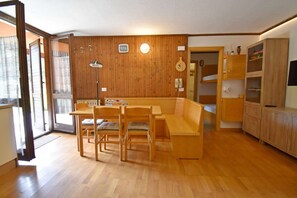 Ein Zimmer mit Holzvertäfelung, einem Esstisch mit Stühlen, einer Bank und eingebauten Holzschränken.