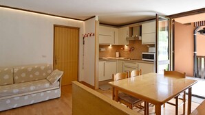 Ett kompakt bostadsutrymme med en soffa, ett matbord och ett litet kök.