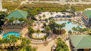 A resort with a pool, lounge areas, and a beach view.