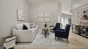 A modern living room with a sofa, two armchairs, a coffee table, and artwork on the walls.