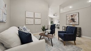 A modern living room with a sofa, armchairs, a coffee table, and artwork on the walls.