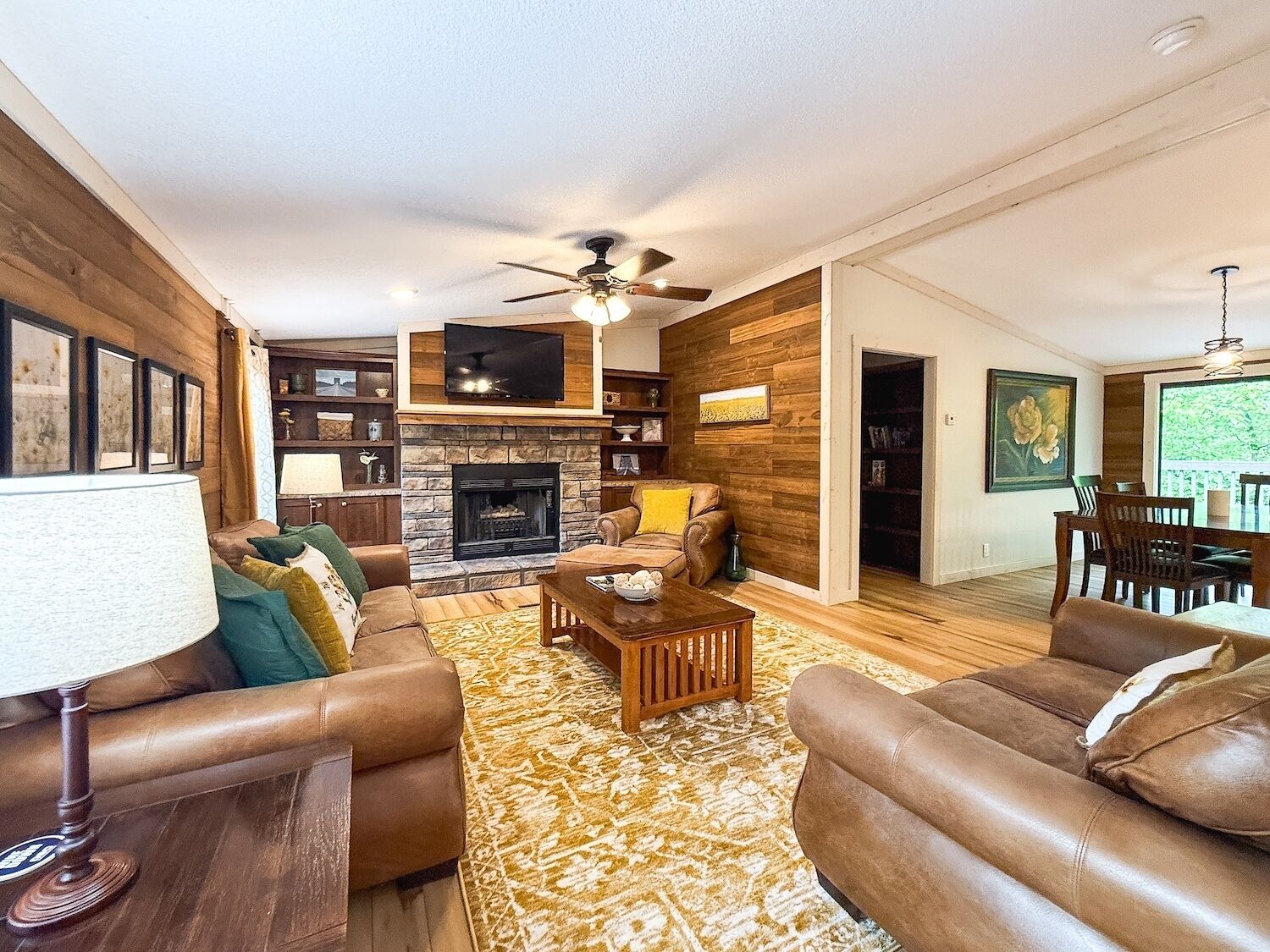 A living room with a fireplace, leather sofas, a coffee table, and a TV mounted on the wall.