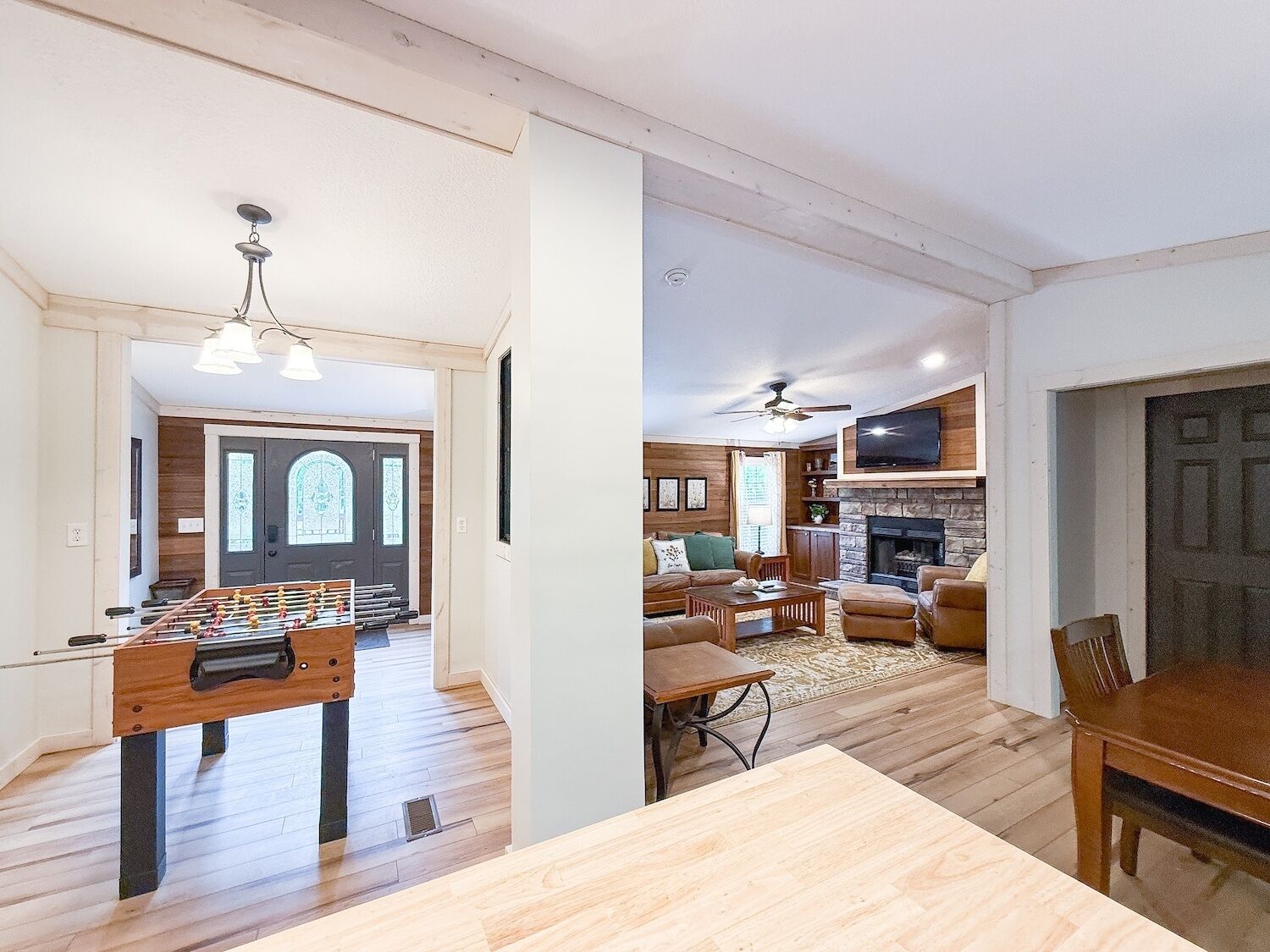 Uma sala de estar ampla com lareira, um espaço de refeições com mesa de futebol e uma área de estar aconchegante.