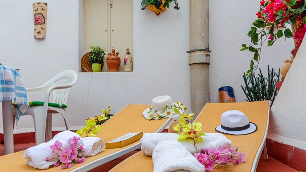 A sunbed with towels and flowers, a white chair, and decorative items on a wall. - YourHouse Ca Na Fonoy (Santa Margalida)