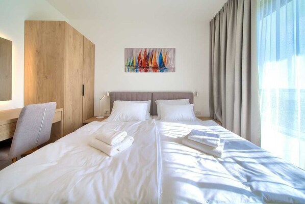 Hotellihuone, jossa on suuri sänky, työpöytä ja taulu seinällä.
