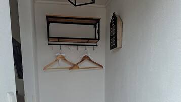 Un pasillo con un banco, perchas de madera y un estante en la pared.
