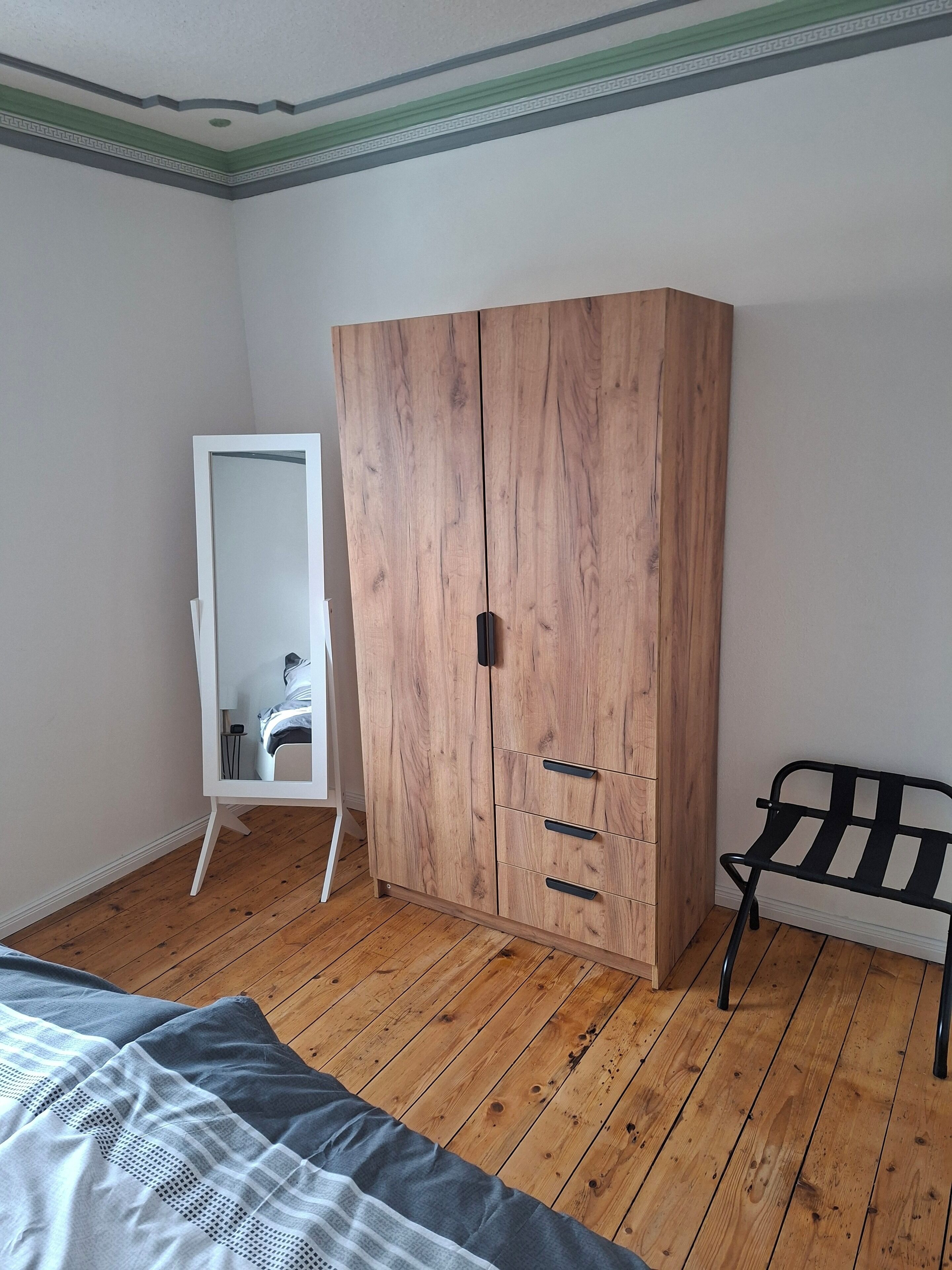 Una camera da letto con un'armadiatura in legno, un letto, una panca e uno specchio.