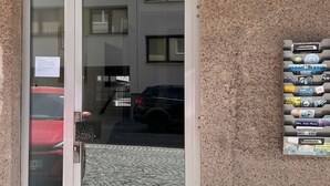 A building entrance with a glass door, a tiled wall, and a signboard with various items. - Modern apartment/city center near (Wien)