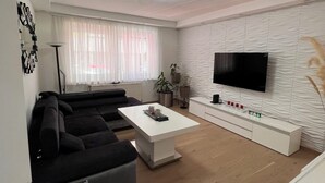 A modern living room with a sectional sofa, a coffee table, a flat-screen TV, and a minimalist design. - Modern apartment/city center near (Wien)