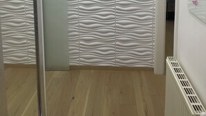A room with a modern design, featuring a textured wall and a wooden floor. There are ceiling lights and a radiator on the wall. - Modern apartment/city center near (Wien)