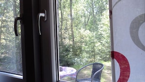 Una ventana con vista a un área boscosa, una silla y una puerta.