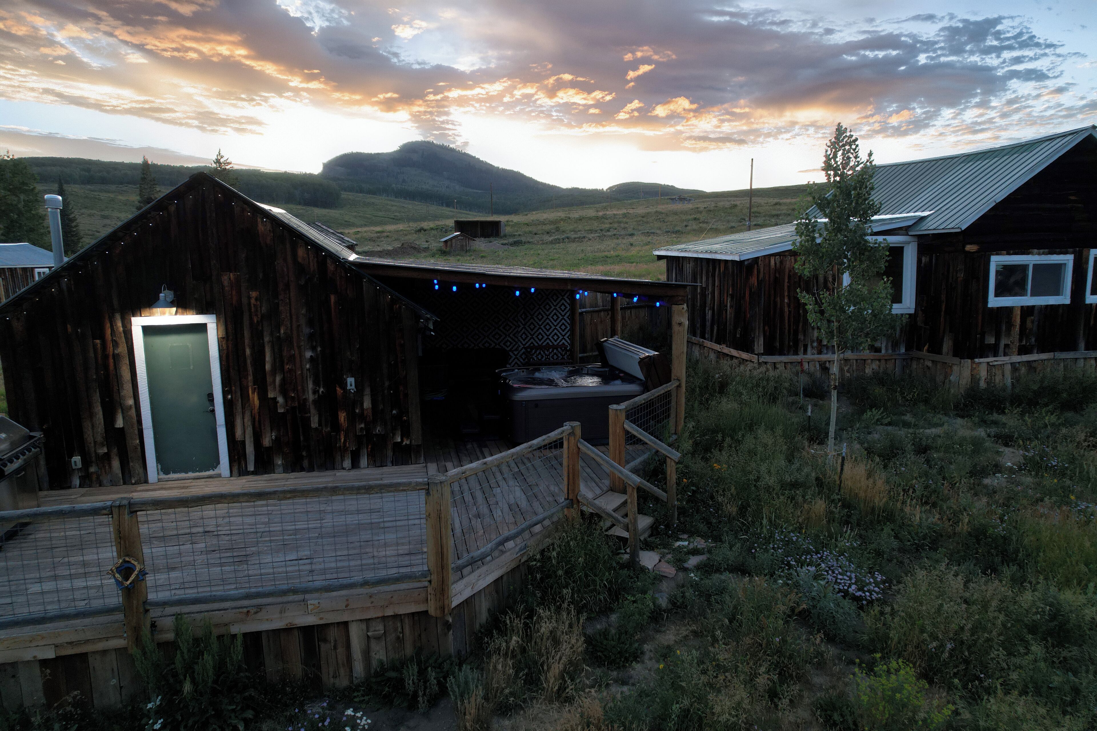A rustic wooden cabin with a deck, a small porch, and a view of the surrounding landscape.