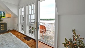 A room with a large sliding glass door leading to a balcony with a wicker chair. - THE RIVERFRONT BOATHOUSE (York)
