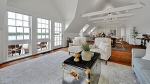A spacious loft with large windows, a cozy seating area, and a kitchen in the background. - THE RIVERFRONT BOATHOUSE (York)