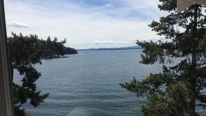 A view of a calm lake with surrounding trees and distant mountains. - Waterfront Cabin at Currents, Otterbay, North Pender Island (Pender Island)