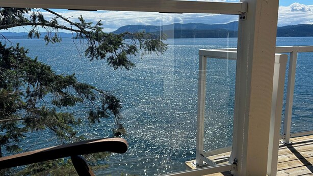 A wooden deck with a bench overlooking a body of water and distant mountains. - Waterfront Cabin at Currents, Otterbay, North Pender Island (Pender Island)
