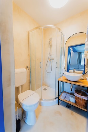 A modern bathroom with a glass-enclosed shower, a white toilet, and a sink with a mirror.
