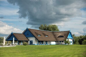 Il s’agit d’un bâtiment traditionnel, doté d’un toit de chaume, d’un porche abrité et d’une pelouse verdoyante.