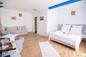 A modern hotel room with a bed, a sofa, a small table, and a wooden floor. - Cherhana Resort (Crisan)