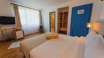 A hotel room with a bed, a desk with a computer, a TV, and a wardrobe.