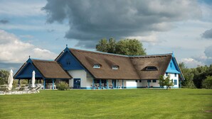 Il s’agit d’un bâtiment traditionnel, doté d’un toit de chaume, d’un porche abrité et d’une pelouse verdoyante.