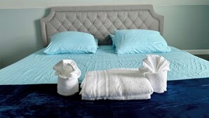 Un lit doté d’une tête de lit capitonnée, de deux oreillers bleu clair et d’une couvre-lit bleu foncé.