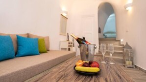 A room with a wooden table, a bottle of champagne, and a plate of fruit.
