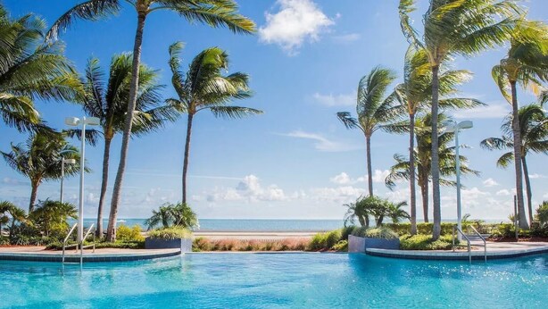 A pool area with palm trees and a view of the ocean. - Hyatt Vacation Club at Windward Point Key West (Key West)