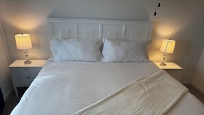 A neatly made bed with white linens and two bedside lamps on matching nightstands. -  3-bedroom bungalow with , WiFi in Jeffersonville (Jeffersonville)