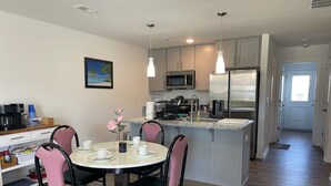 A modern kitchen with a central island, stainless steel appliances, and a dining area with chairs and a table. -  3-bedroom bungalow with , WiFi in Jeffersonville (Jeffersonville)