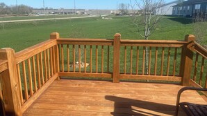 A wooden deck with a railing overlooking a grassy area and a clear blue sky. -  3-bedroom bungalow with , WiFi in Jeffersonville (Jeffersonville)