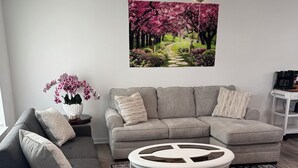 A modern living room with a gray sectional sofa, a round coffee table, and a decorative rug. -  3-bedroom bungalow with , WiFi in Jeffersonville (Jeffersonville)