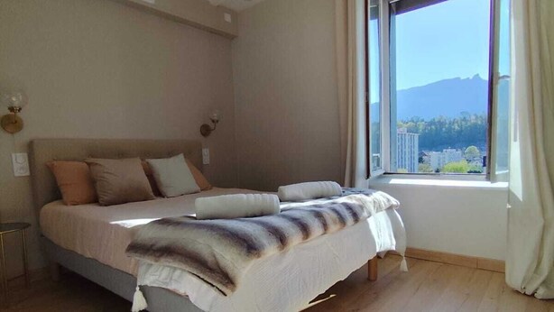 Ein Schlafzimmer mit einem großen Bett, einem Fenster mit Bergblick und Holzböden.
