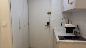 Eine kleine Küche mit weißen Schränken, einer schwarzen Arbeitsplatte und Holzboden.