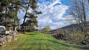 A house with a stone wall, a lawn, and a mountain in the background.