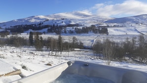 A snow-covered landscape with a hot tub in the foreground.