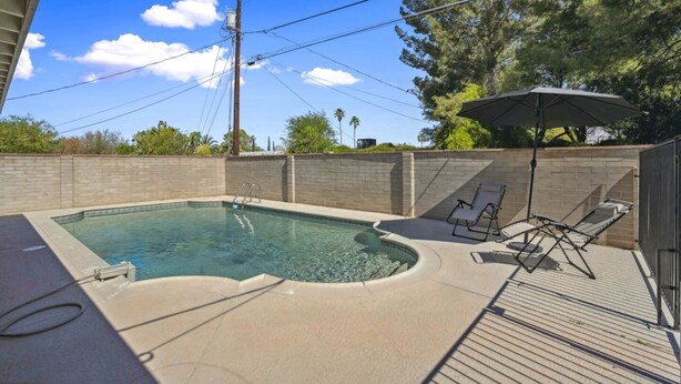A swimming pool with a built-in hot tub, surrounded by a brick wall and a wooden deck. - Boho on Bermuda with Private Pool in Tucson (Tucson)