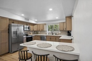 Una cocina moderna con una isla central, electrodomésticos de acero inoxidable y armarios de madera.