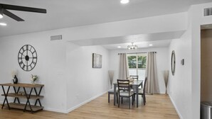 A spacious dining area with a wooden table and chairs, a ceiling fan, and a clock on the wall. - Boho on Bermuda with Private Pool in Tucson (Tucson)