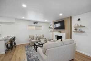 Una sala de estar moderna con un sofá, una mesa de centro, un televisor y una chimenea.