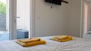 Habitación de hotel con cama, televisor montado en la pared y puerta que da a un espacio al aire libre.