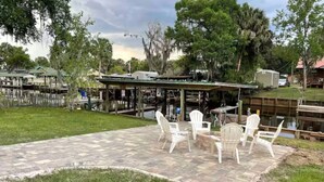 A patio with outdoor seating and a view of a dock and water. - 3 BR 2 BA House w/Dock on Deep Canal in Bass Capital (Crescent City)