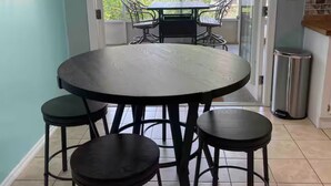 A dining area with a round table and four stools, a ceiling light fixture, and a view through a glass door to an outdoor patio. - 3 BR 2 BA House w/Dock on Deep Canal in Bass Capital (Crescent City)