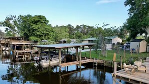 A waterfront property with docked boats, a wooden deck, and a small building. - 3 BR 2 BA House w/Dock on Deep Canal in Bass Capital (Crescent City)